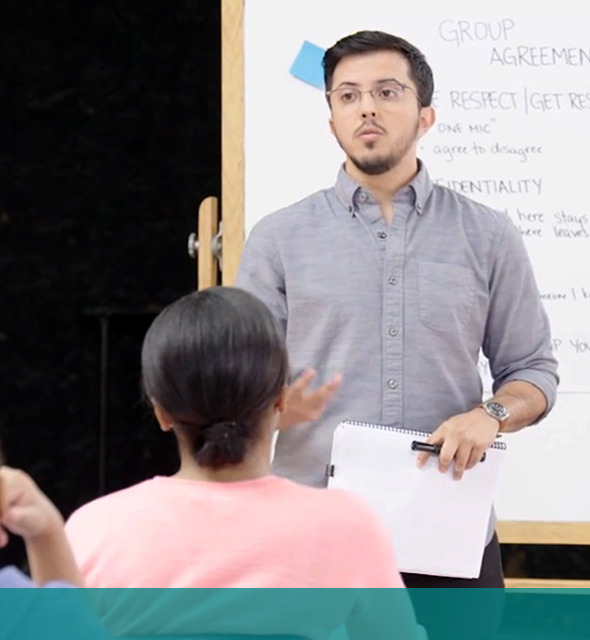 A man speaking in front of a whiteboard