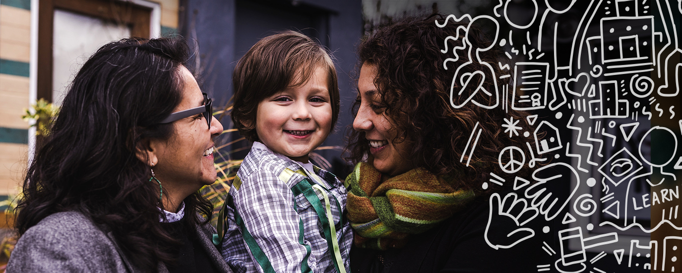 Two women smiling and looking at a child